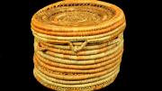 A round, yellow and orange, coiled basket with a lid but no handle. 